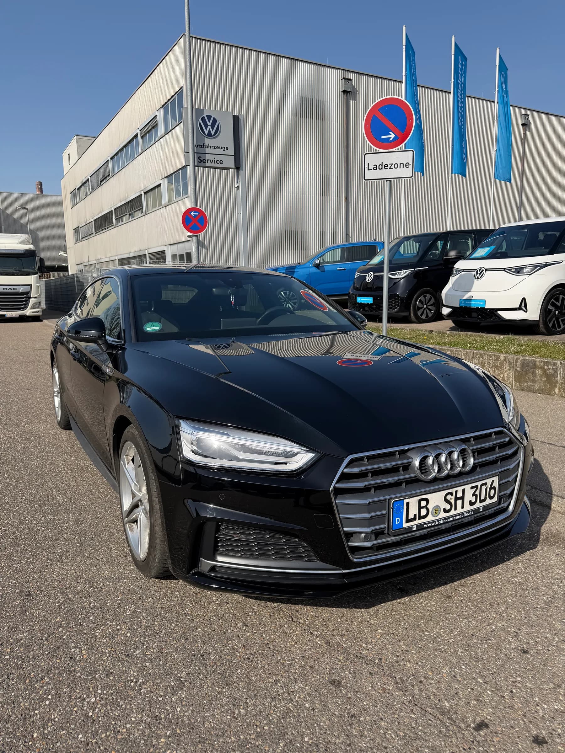 Schwarzer Audi A5 Sportback in der Frontansicht, abholbereit vor dem Betrieb.