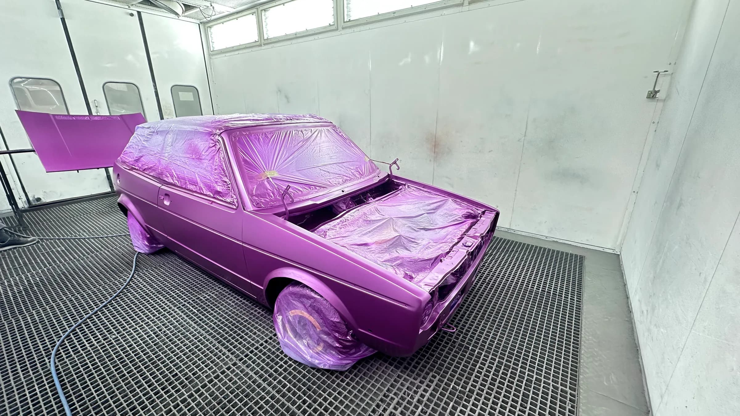 VW Golf der ersten Generation in kräftigem Lila-Metallic, frisch lackiert in der Lackierkabine.