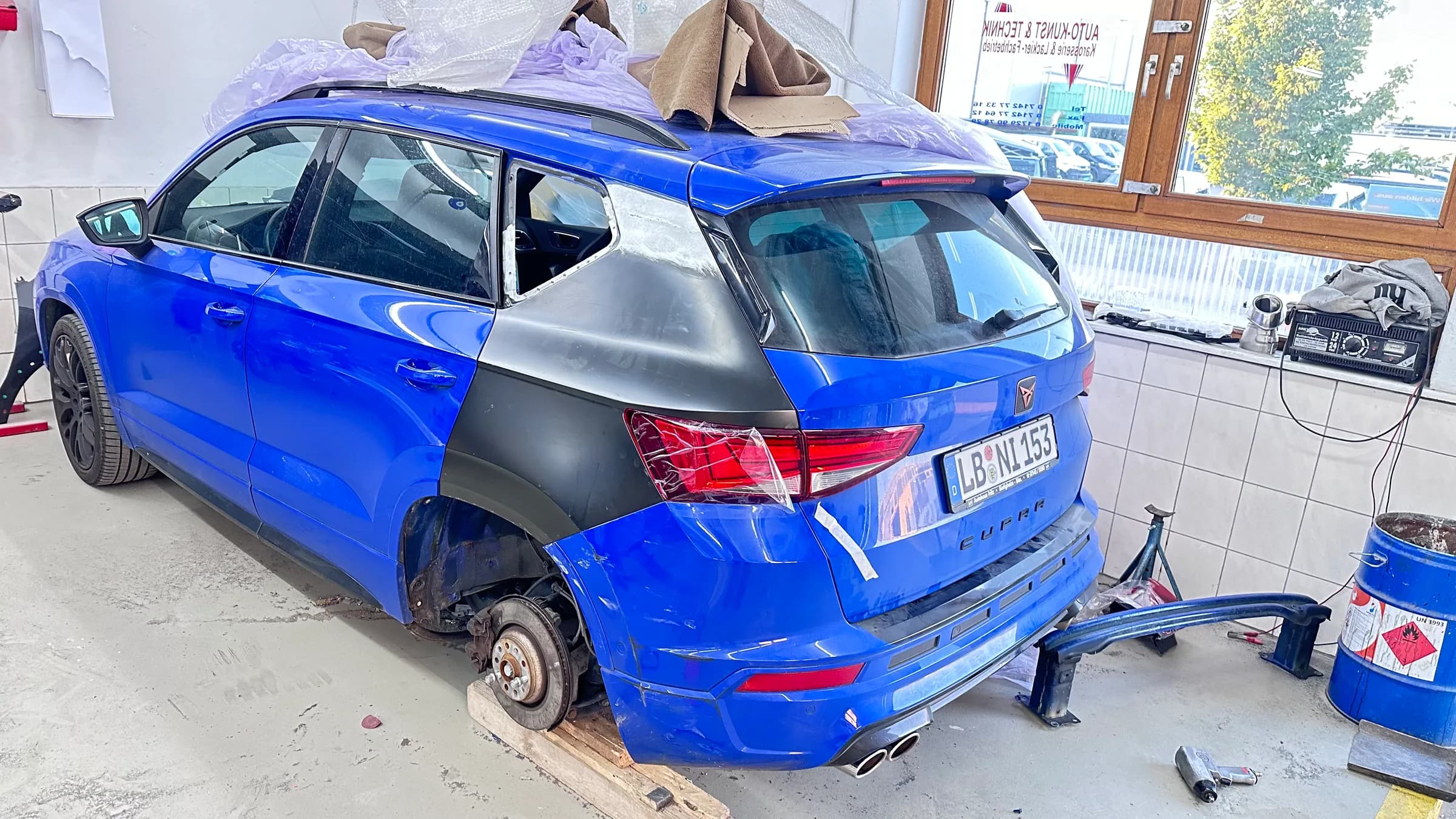 Blauer Kombi mit ausgetauschter hinterer Seitenwand: Das neue Blechteil steckt noch in grauer Grundierung, der Rest des Fahrzeugs ist bereits blau lackiert.