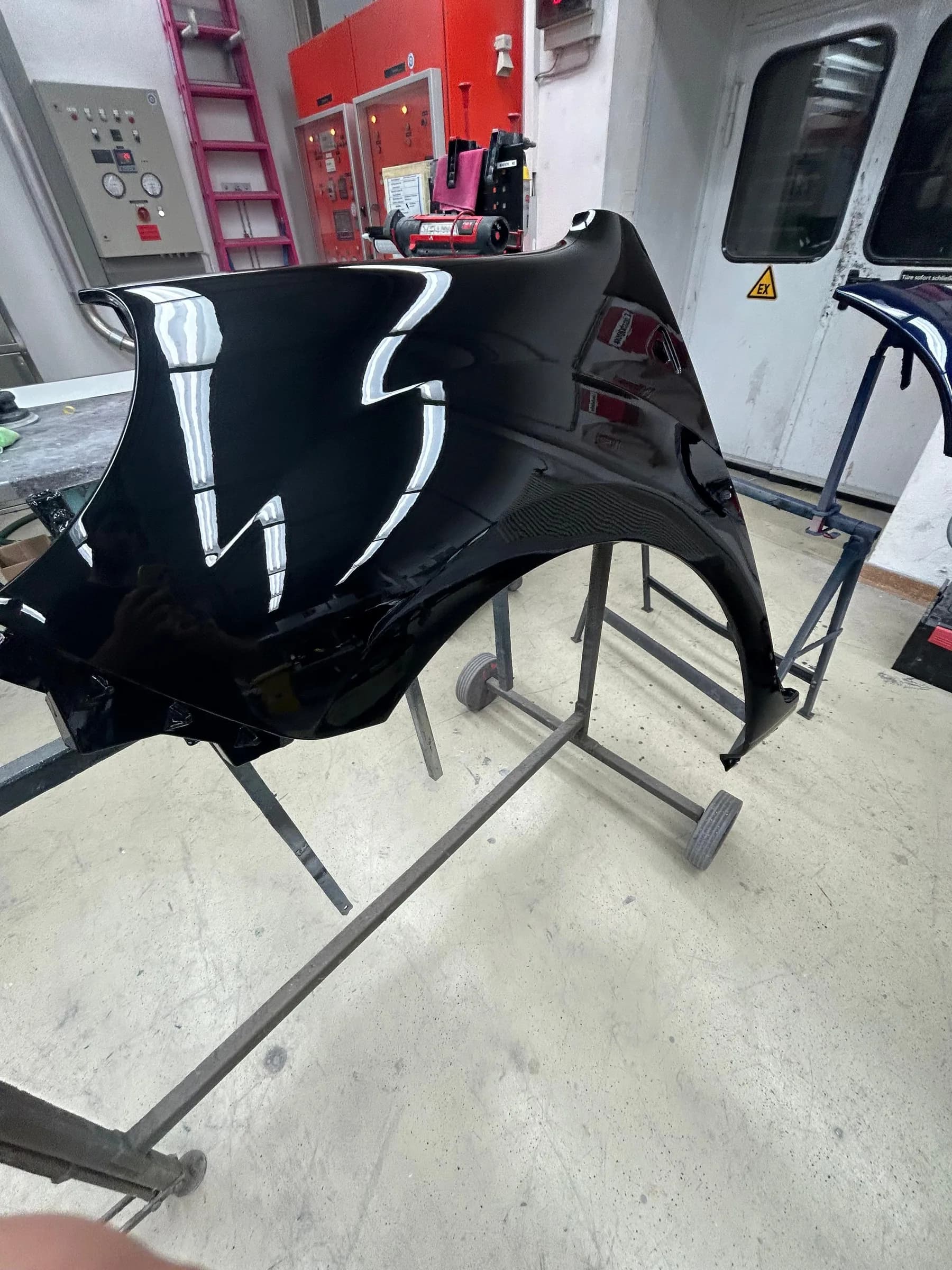 Schwarz lackierte Motorhaube auf einem Lackierständer in der Vorbereitungszone.