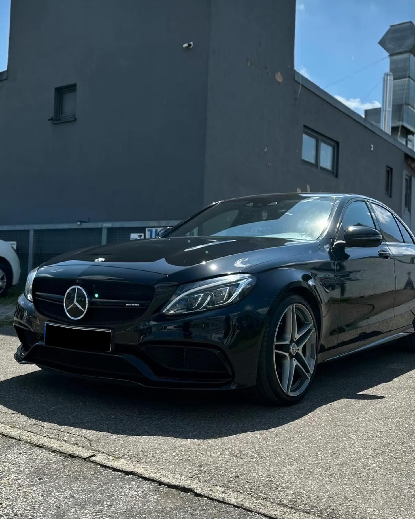 Fertig instandgesetzter Mercedes-AMG C 63 in Schwarz vor der Werkstatt