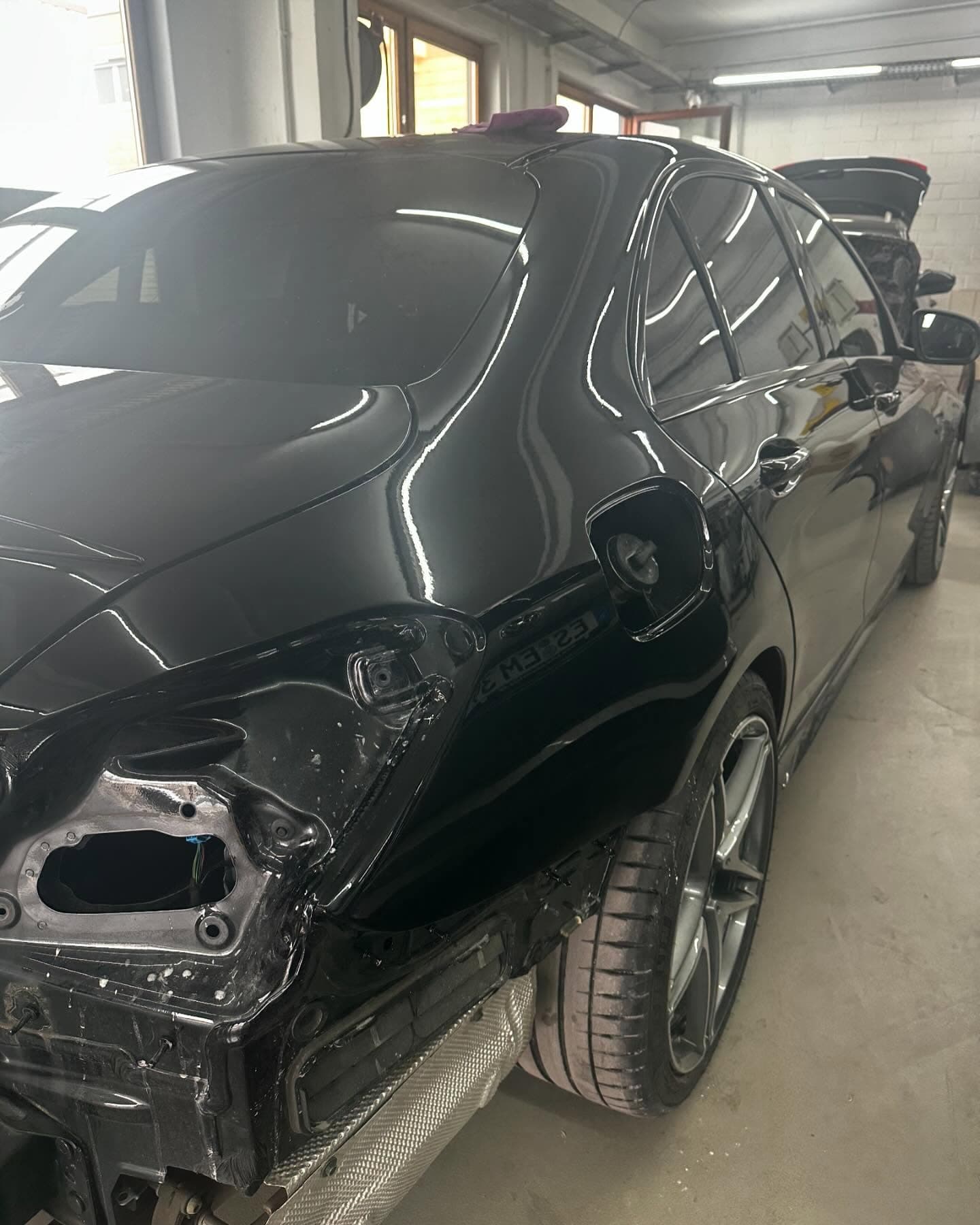 Schwarzes AMG-Coupé mit beschädigter Front in der Werkstatt